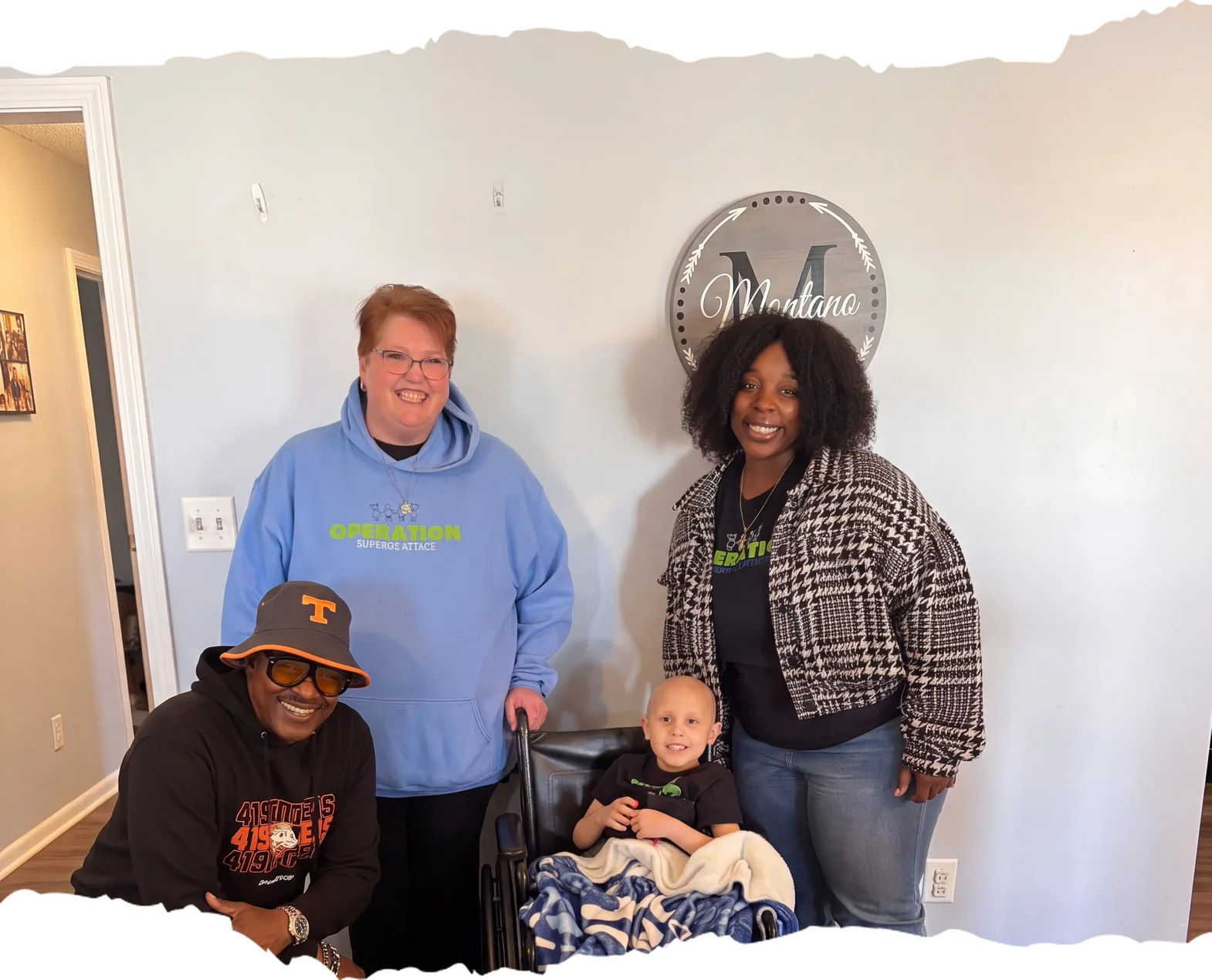 Three Operation Surprise Attack team members with a smiling boy in a wheelchair at his home on delivery day