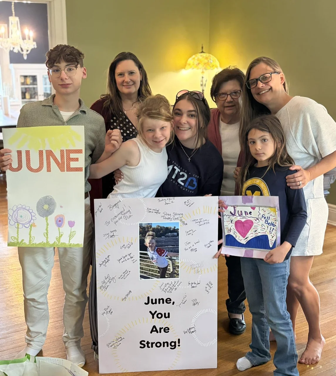 June's family holding the signed poster and handmade cards made for her