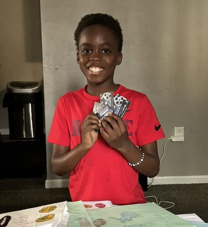 A boy smiling behind a wall of card drawings
