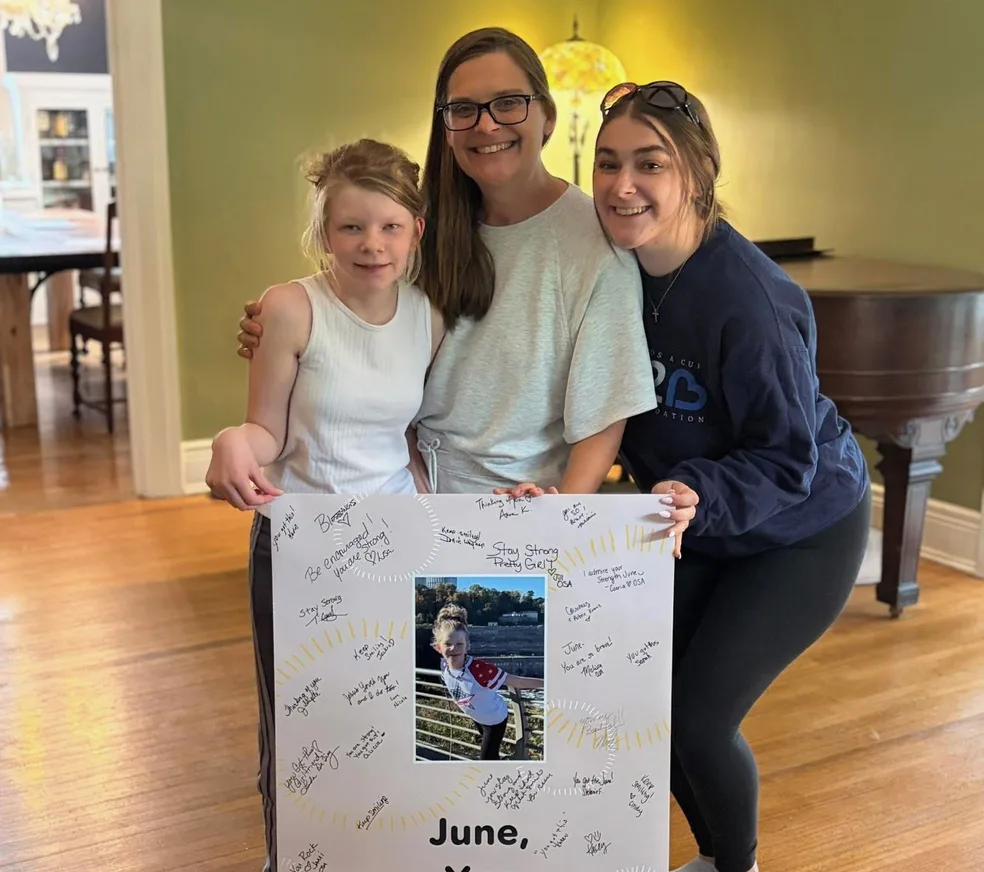 June with her family holding the signed “June, You Are Strong” poster